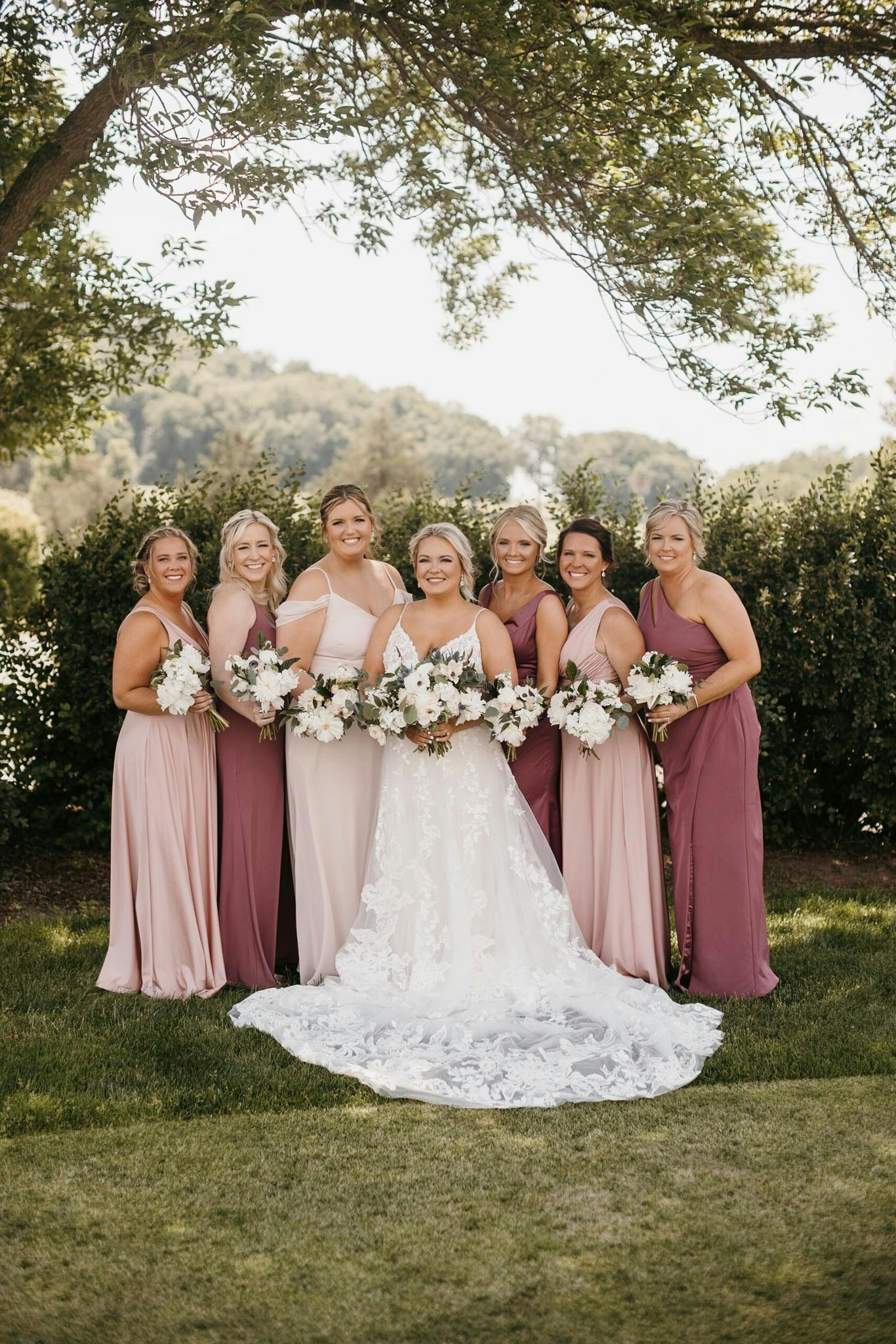 Picture of Bride with all her bridesmaids behind her in front of bushes