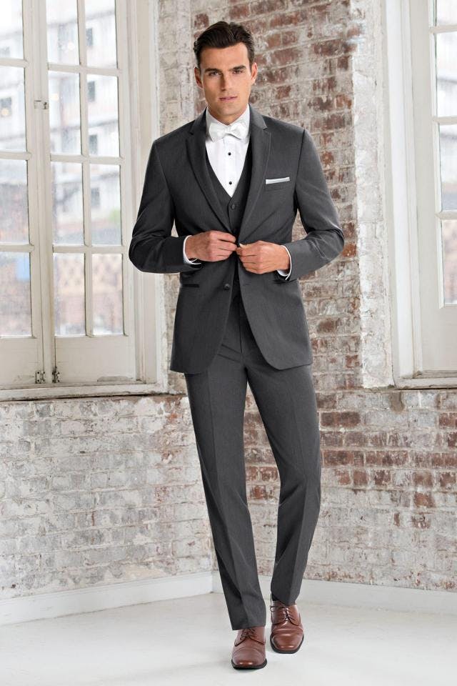 Picture of man in dark grey tux inside building with brick walls
