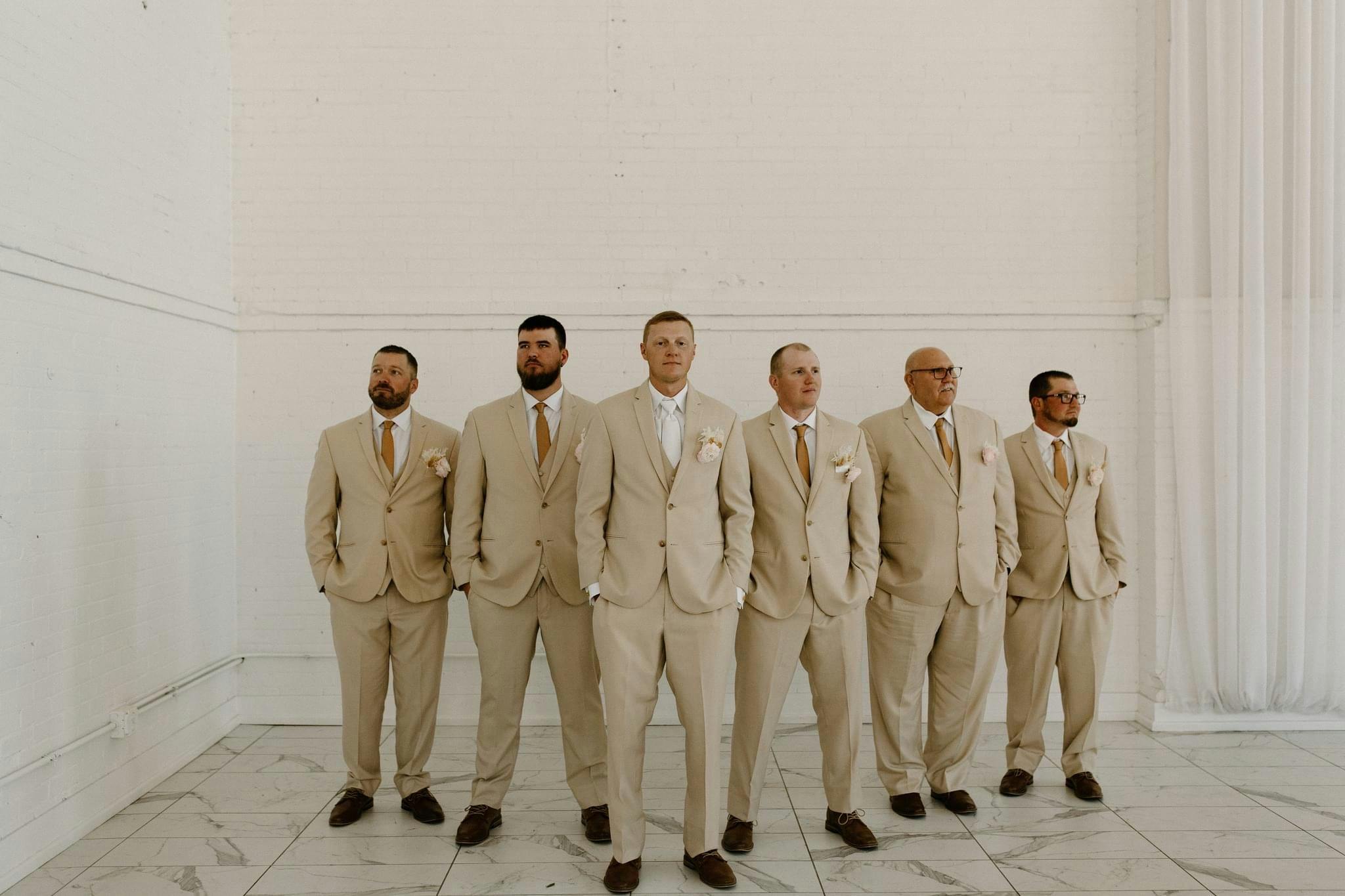 Picture of Groom standing in a triangle formation in front of his groomsmen all wearing matching suits