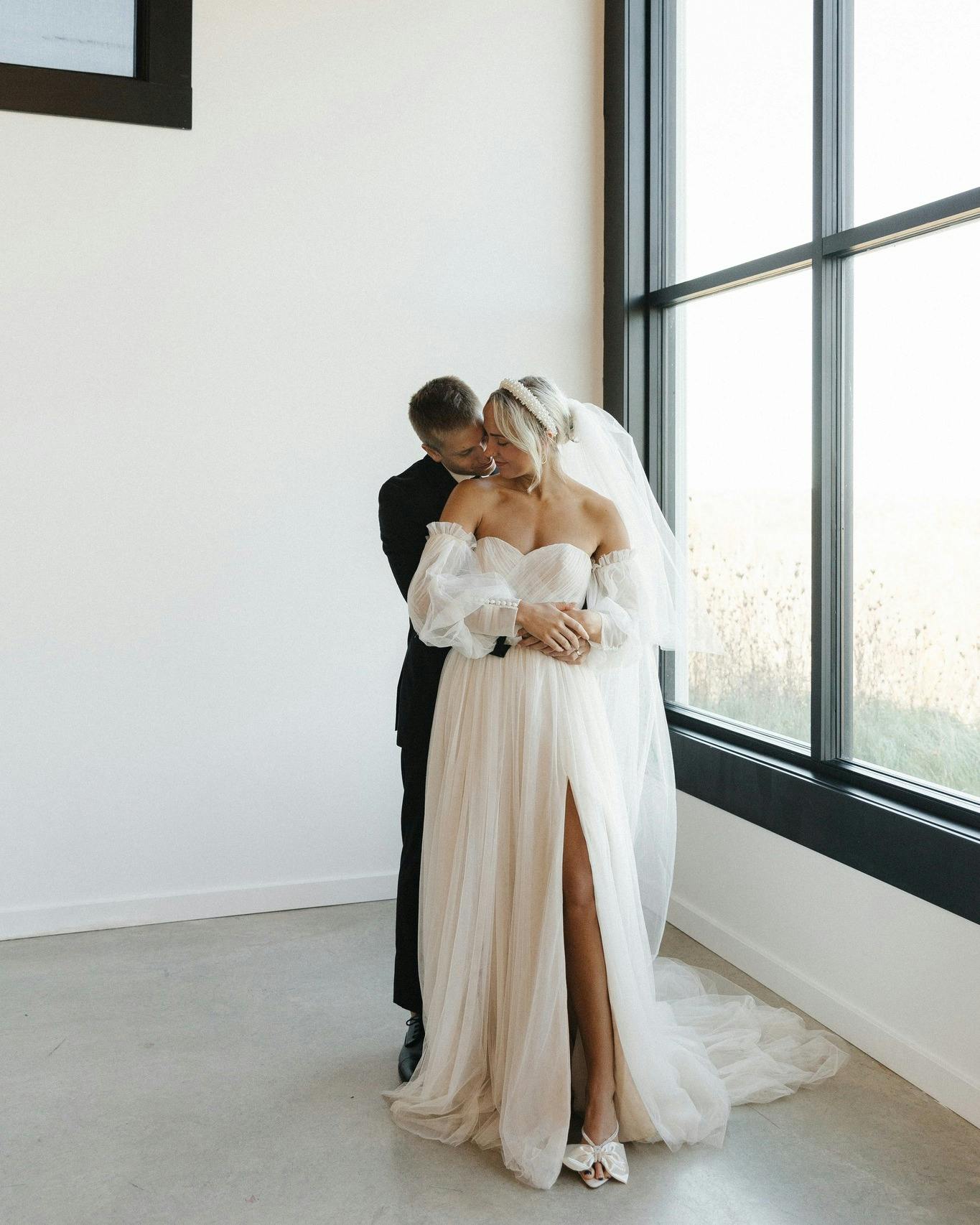 Picture of Groom holding bride in a white room with a big window